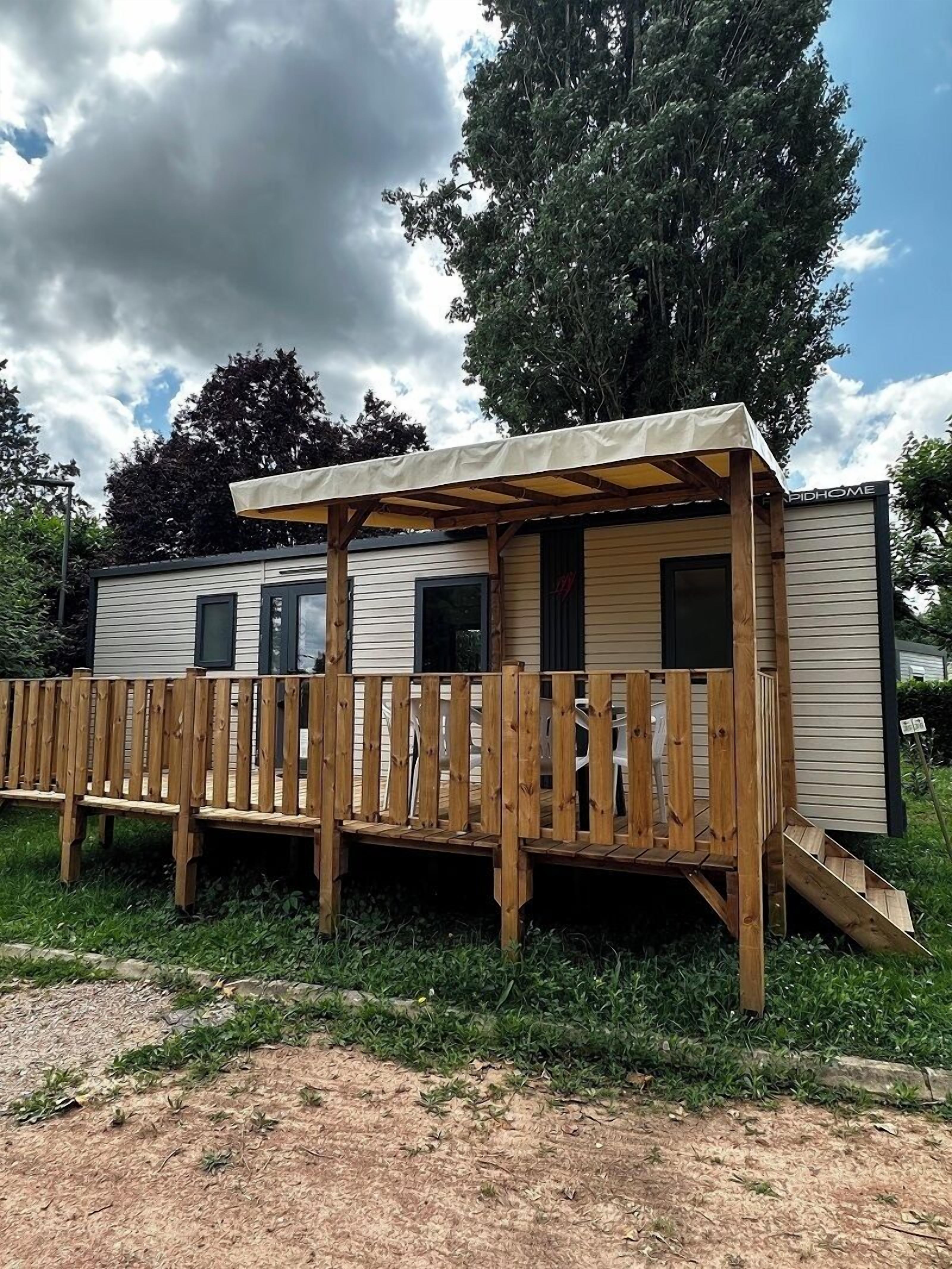 A mobile home with a wooden deck and a covered porch.