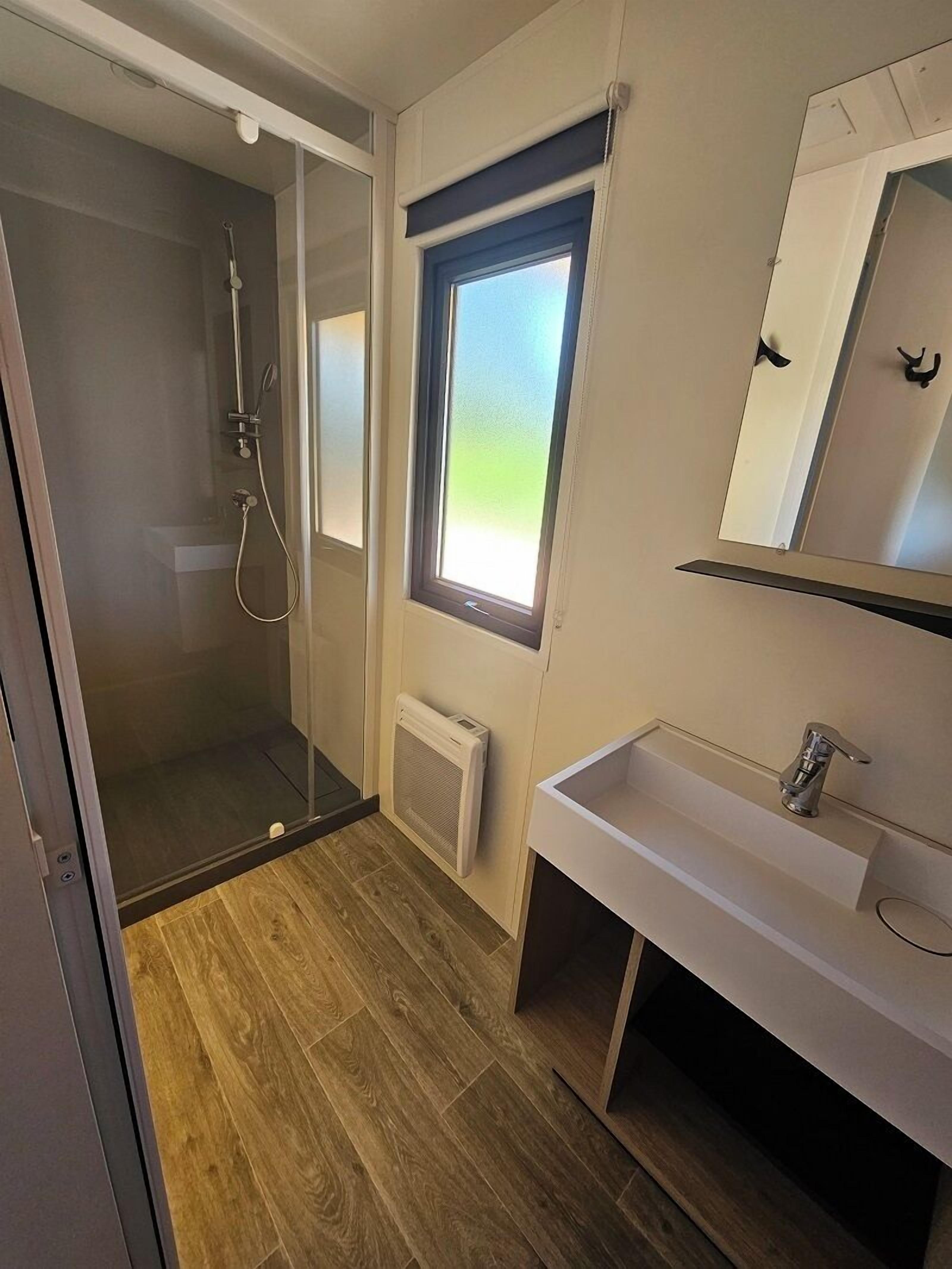 Une salle de bain avec une douche, une fenêtre et un lavabo.