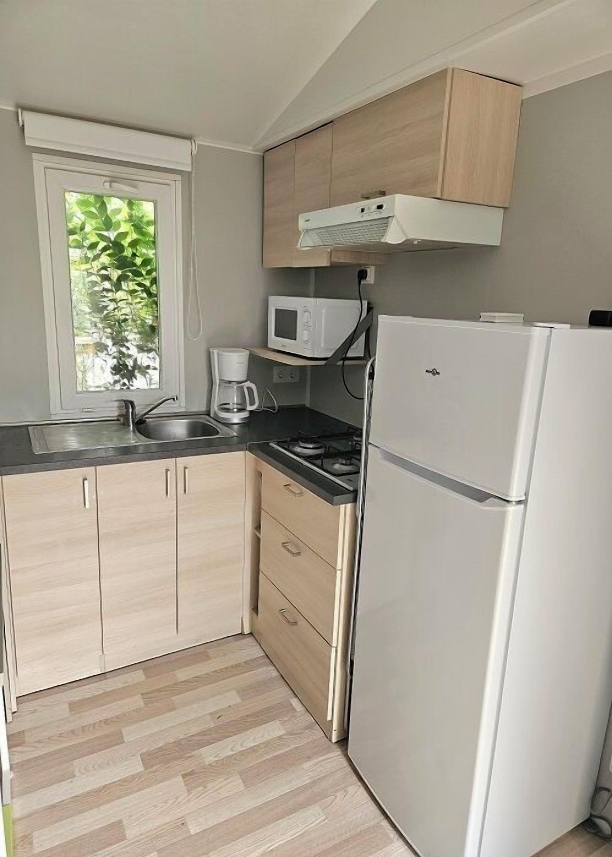 A compact kitchen with a built-in microwave, a coffee maker, and a refrigerator.