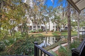 A view of a building with multiple floors, surrounded by trees and a small pond. - Beach Access, Celebration Park & Coligny Plaza (Hilton Head Island)