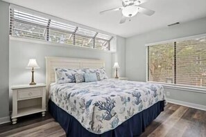 A bedroom with a bed, nightstands, a ceiling fan, and windows with blinds. - Beach Access, Celebration Park & Coligny Plaza (Hilton Head Island)