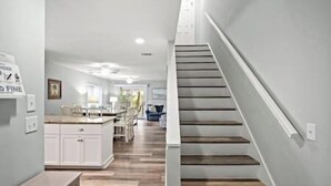 Een moderne keuken met witte kasten, een houten aanrecht en een eethoek met stoelen.