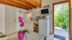 A compact kitchen with a microwave, a small sink, and a wooden ceiling. - Villa Désirée Agde – Guest Room with Private Terrace and Garden (Agde)