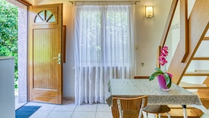 A room with a wooden door, a table with a tablecloth, a chair, a potted plant, and a staircase. - Villa Désirée Agde – Guest Room with Private Terrace and Garden (Agde)