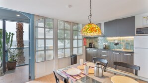 Une cuisine moderne avec un coin repas, de grandes fenêtres et un luminaire suspendu.