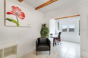A modern room with a white wall, a black leather chair, a desk with a computer, and a window with a view of wind turbines. - Holiday Apartment 'El Doctoral' with Sea View, Wi-Fi and Air Conditioning (El Doctoral)