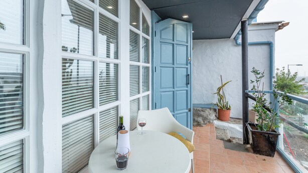 Une terrasse avec une table, des chaises, des plantes en pot et une porte bleue.