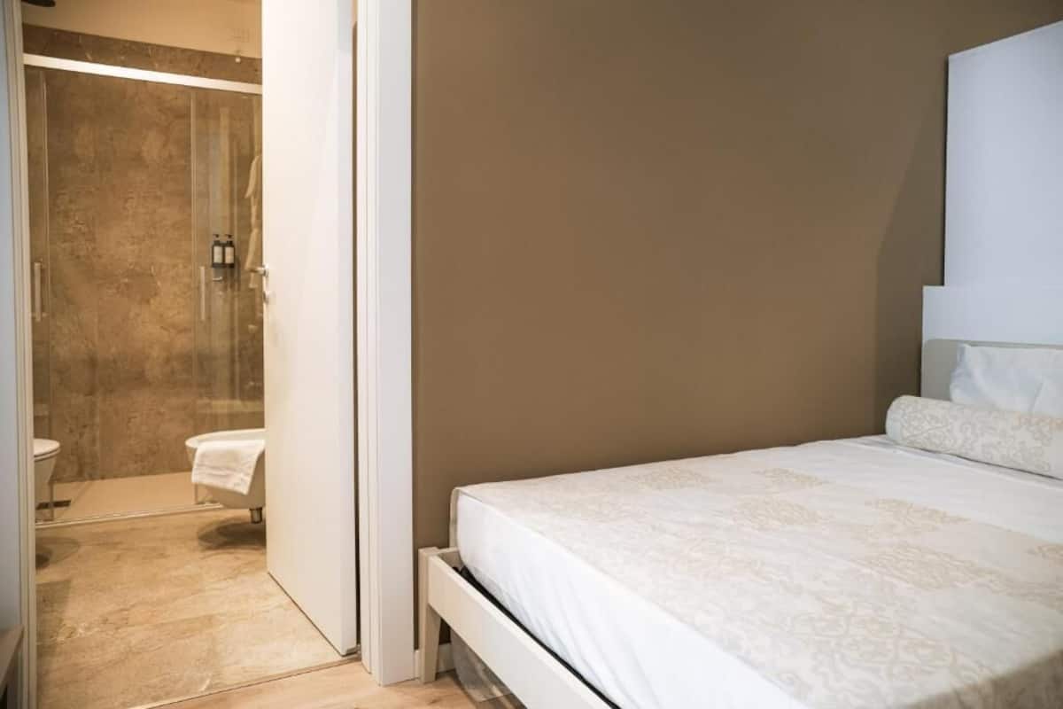 A bedroom with a bed, a bathroom with a shower, and a toilet.