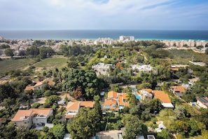 An aerial view of a coastal residential area with houses, greenery, and a view of the sea. - Relax in a Garden Oasis by Sea N' Rent (Nahariya)