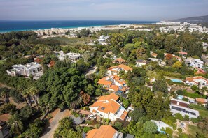Vista aérea de una zona residencial con casas, árboles y una costa.