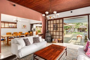 Amplia sala de estar con sofá blanco, mesa de centro de madera y un ventanal con vistas al jardín trasero.