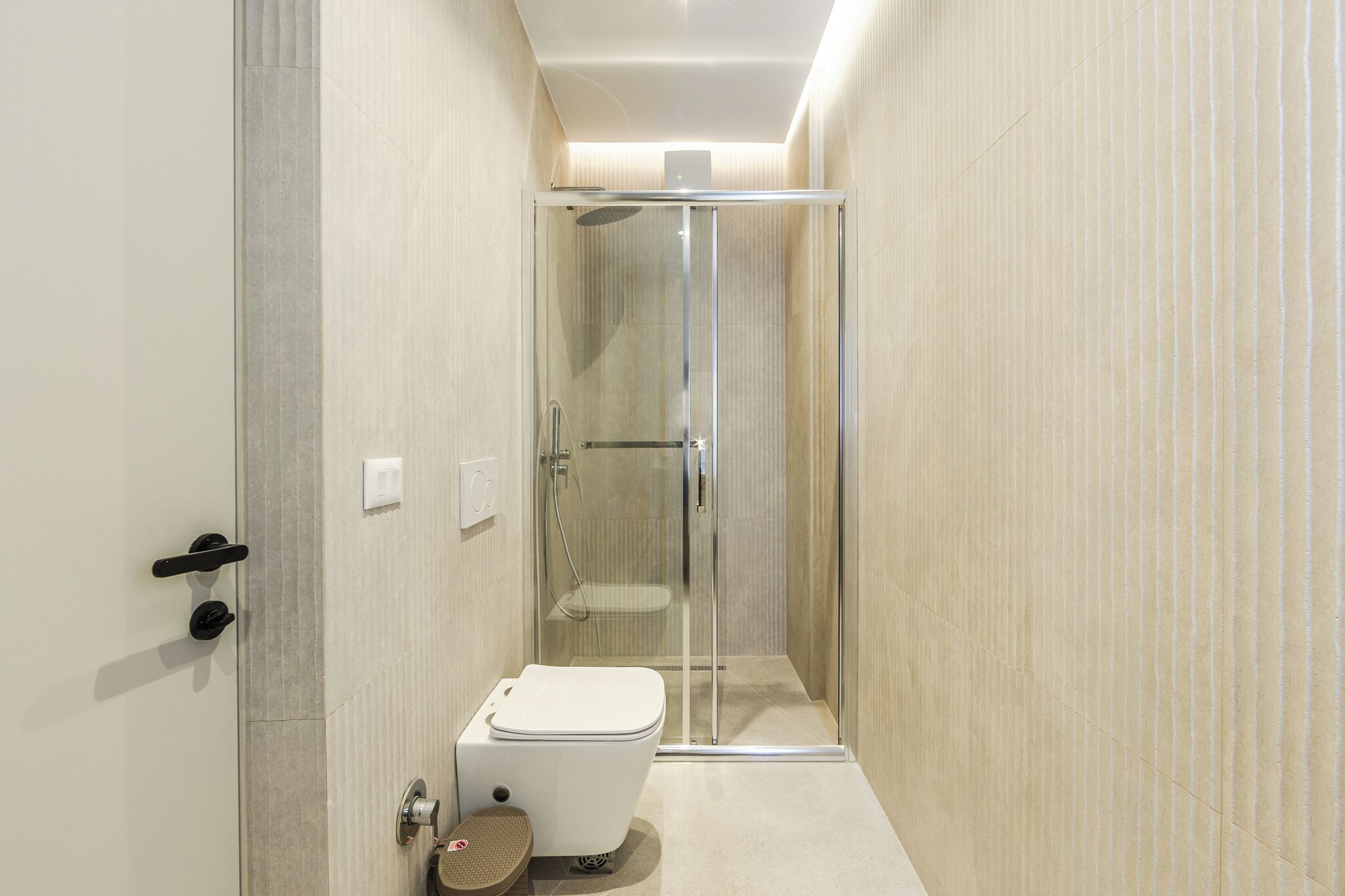 A modern bathroom with a glass-enclosed shower, a toilet, and a sink.