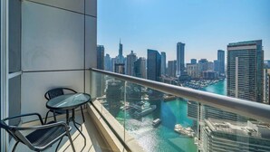 En balkon med gelænder af glas, udsigt over byens skyline og et vandareal med både.