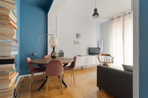 Un soggiorno moderno con zona pranzo, televisore e libreria.
