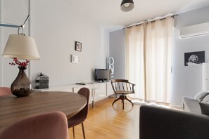Ein modernes Wohnzimmer mit Esstisch, Stühlen, Fernseher und einer Couch.