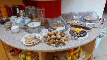 Ein Buffet mit verschiedenen Speisen, darunter Gebäck, Kuchen und Früchte.