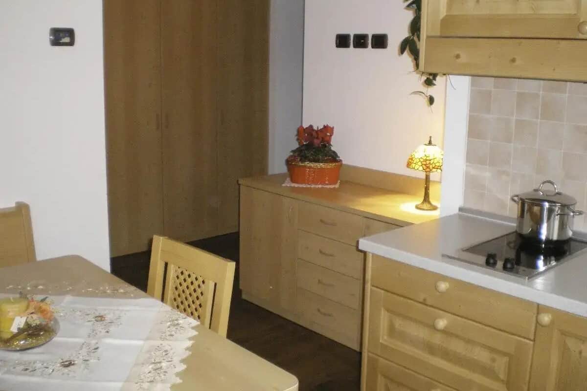 Een kleine keuken met een eettafel, een kastje met een plant en een fornuis.