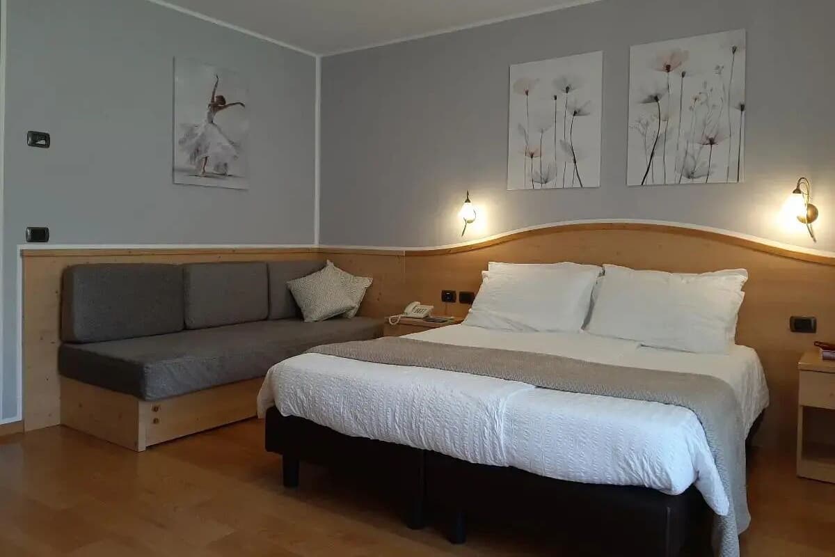 Een slaapkamer met een bed, een slaapbank en twee wandlampen.