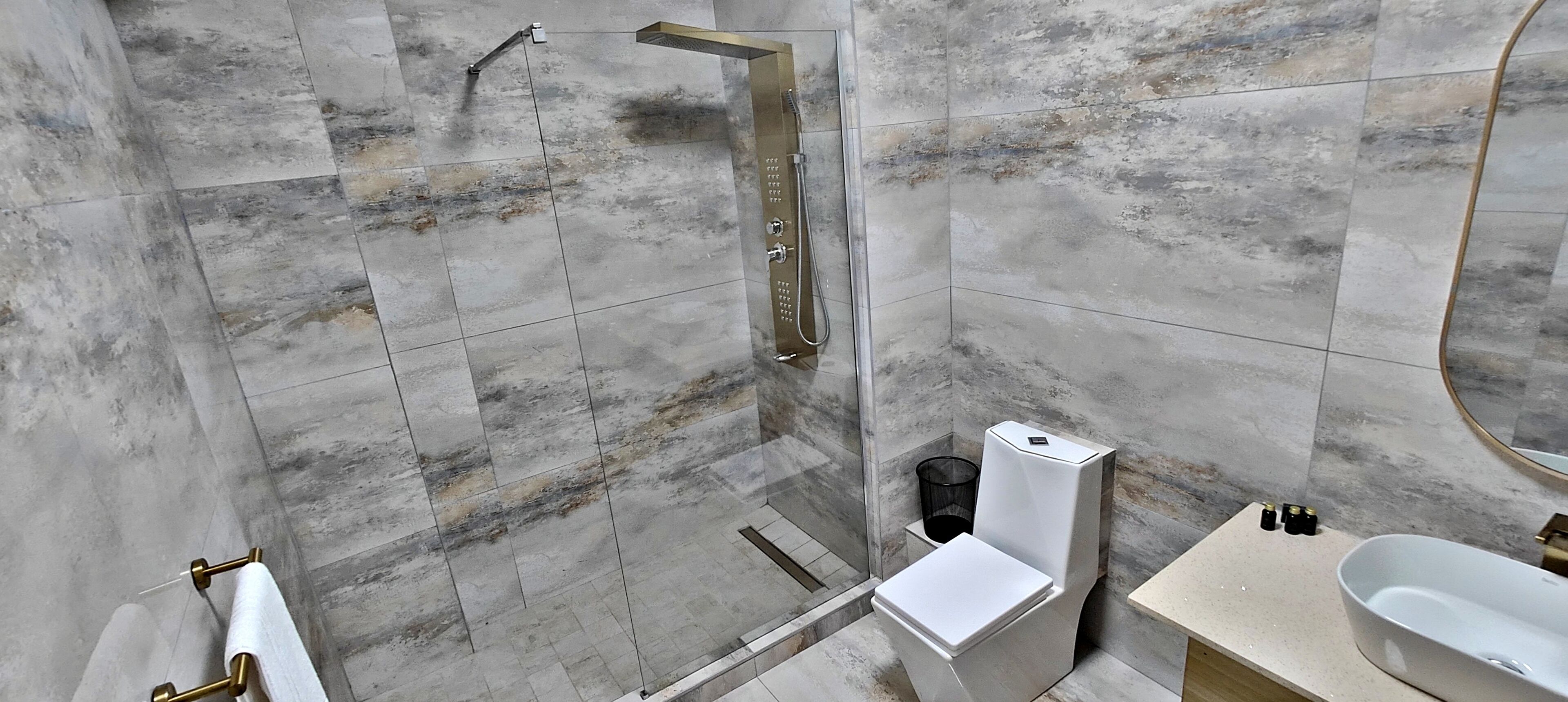 Ein modernes Badezimmer mit bodenebener Dusche, Toilette und Waschbecken.