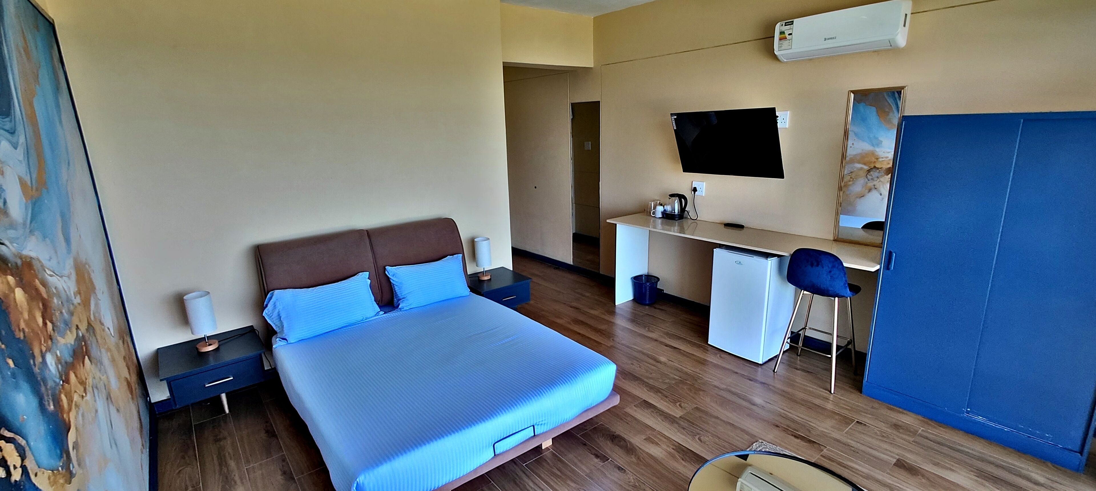 A bedroom with a bed, desk, chair, and a wardrobe.