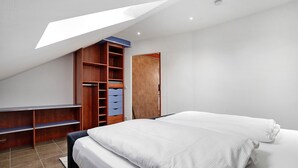 Une chambre avec un puits de lumière, un lit, une armoire et un bureau.