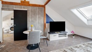 Un salon moderne comprenant un coin repas, un téléviseur à écran plat et une lucarne.