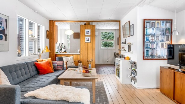 Una sala moderna con un sofá gris, detalles de madera y una televisión.