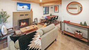 Una sala de estar acogedora con chimenea, un comedor y un espejo grande.