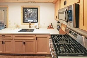 A kitchen with a stainless steel stove, a microwave, and wooden cabinets. - PET FRIENDLY 🐾! Foosball! Two Living Rooms! Modern Living! (Big Bear Lake)