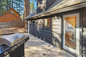Ein Holzhaus mit überdachter Terrasse, Grill und einer Schiebetür.