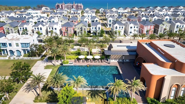 Ein Resort mit Schwimmbad, umgeben von Palmen und Blick auf den Ozean.