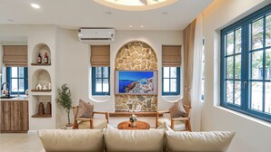 Ein modernes Wohnzimmer mit Steingewölbe, Flachbildfernseher, einer Couch und Blick ins Freie.