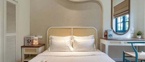 Una cama bien hecha con sábanas blancas, una mesita de noche con lámpara y una silla con asiento de fibras naturales.