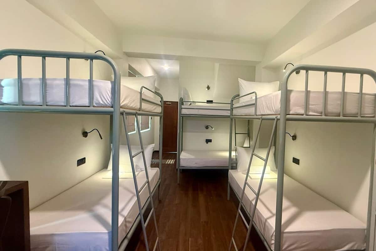 Dormitorio con tres literas, suelo de madera y una puerta con la etiqueta 'D1'.