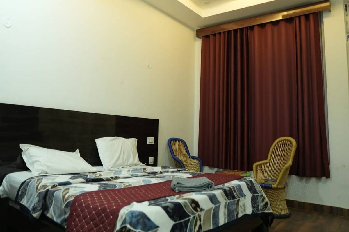 Un dormitorio con cama, ventilador de techo, ventana con cortinas y una silla.