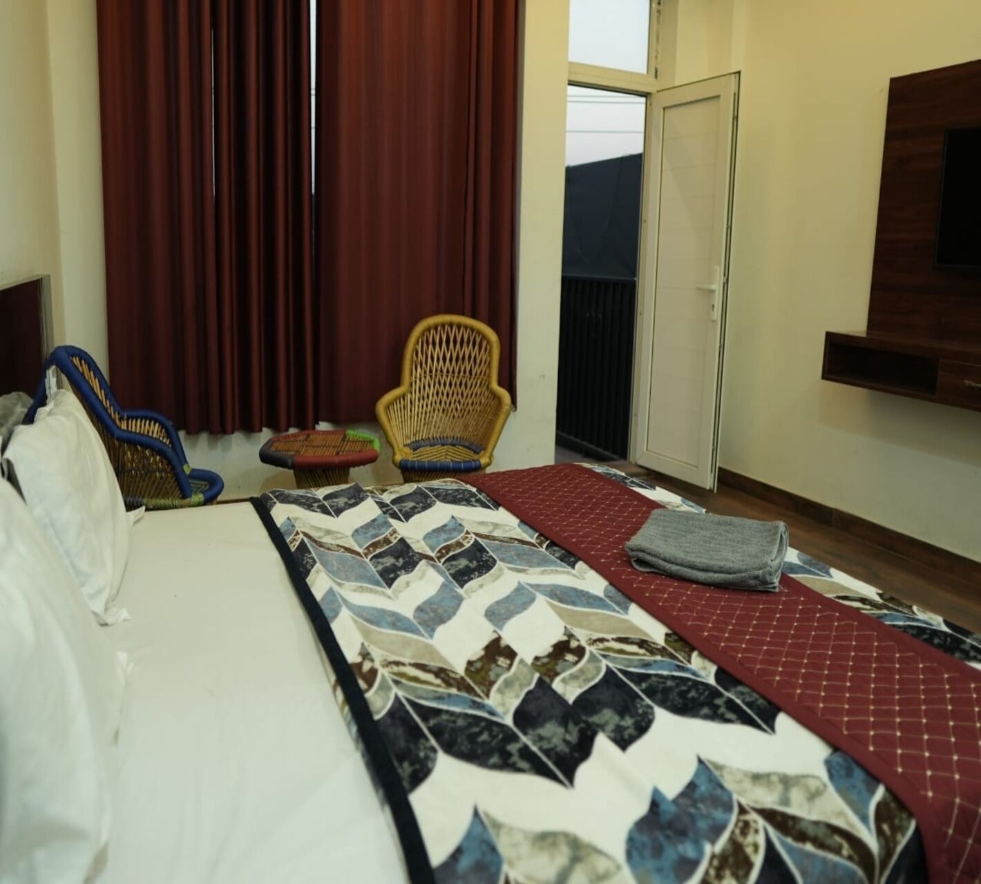 Una habitación de hotel con cama, una silla, una mesita y una ventana con cortinas.