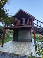 Una pequeña construcción de madera con balcón, una puerta verde y una escalera que conduce a ella.