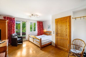 A bedroom with a wooden bed, a chair, a desk, and a wardrobe. - Apartment 'Nr-35qm' with Shared Garden and Wi-Fi (Vogtsburg)