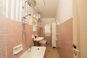 A bathroom with a bathtub, two sinks, a toilet, and a shower.