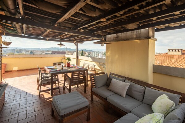 An outdoor patio with a table and chairs, a sofa, and a view of the city.