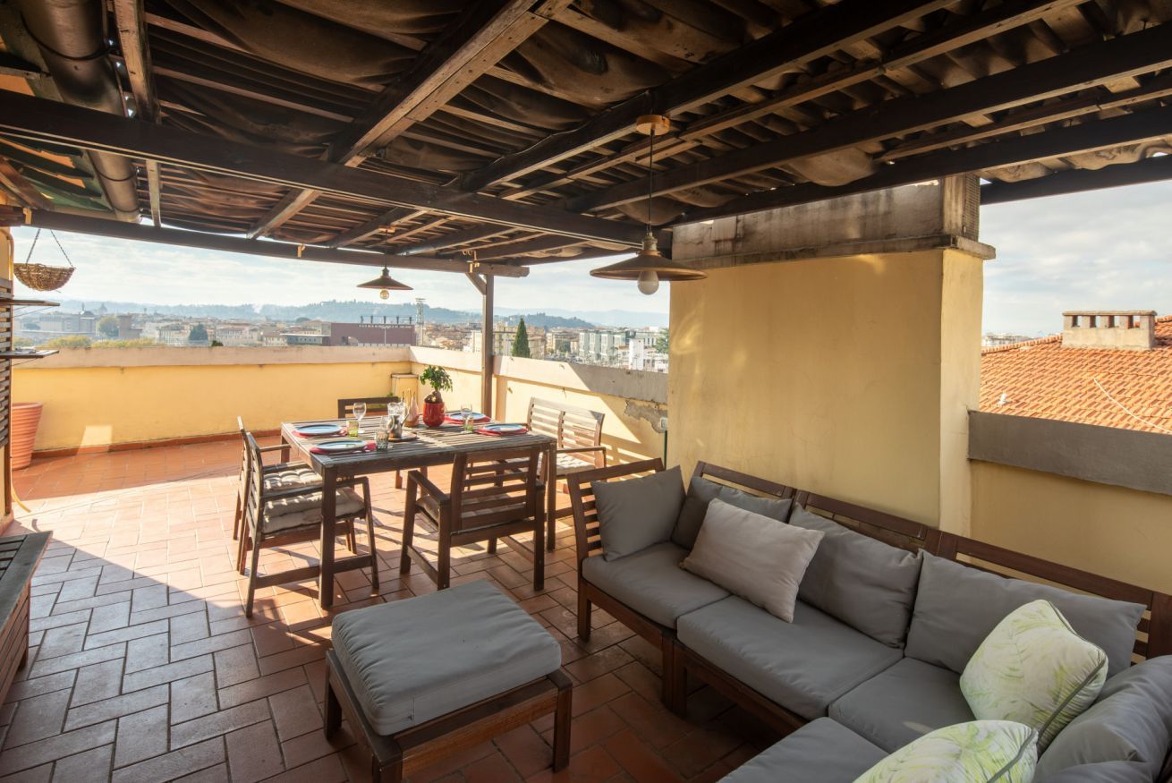 Une terrasse extérieure avec une table et des chaises, un canapé et une vue sur la ville.