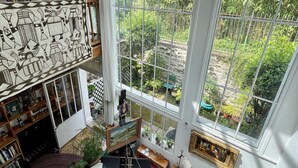 En rummelig stue med et stort vindue, et opholdsrum med kunst og et hyggeligt siddeområde med pejs.