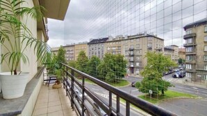 A balcony with potted plants, overlooking a residential street with multi-story buildings. - Fantastic Inn Kraków - Słowackiego (Kraków)
