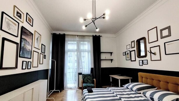 A hotel room with a bed, a chair, a desk, and a view of the street through the window. - Fantastic Inn Kraków - Słowackiego (Kraków)