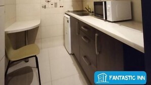 A compact kitchen with dark cabinets, a microwave, and a small dining area. - Fantastic Inn Kraków - Słowackiego (Kraków)