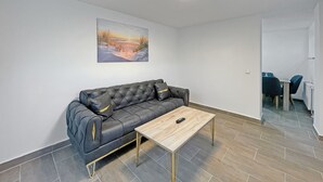Una sala de estar moderna con un sofá de cuero, una mesa de centro de madera y un cuadro en la pared.