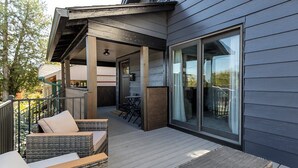 Ein überdachter Außenbereich mit Korbmöbeln, einem Holzboden und einer Glastür, die zu einem Balkon führt.