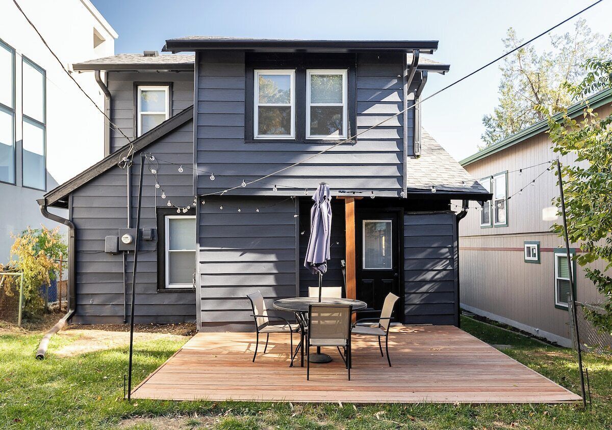 Ein zweistöckiges Haus mit einer Terrasse, einem Patio-Tisch und Stühlen.