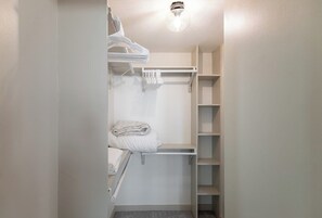 Ein begehbarer Kleiderschrank mit Regalen und Kleiderstangen, einer Lampe und einem Handtuchhalter.