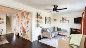 Ein Wohnzimmer mit einer Couch, einem Couchtisch, einem Fernseher und einem Deckenventilator.